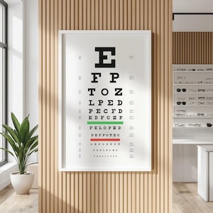 May include: A framed eye chart with black letters hangs on a wooden wall in an optometrist's office. The chart displays rows of letters, with the letters getting progressively smaller. A green line highlights a row of letters. The office has a modern design.