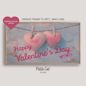 May include: A digital art print featuring two pink hearts hanging on a clothesline with the names "Josh" and "Emily" written on them. The text "Happy Valentine's Day" is written below the hearts with two small hearts on either side of the text. The background is a light blue wooden surface.