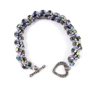 May include: A beaded bracelet with a heart-shaped clasp. The bracelet is made with small, square beads in shades of green, purple, and blue.