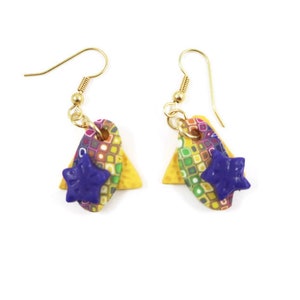 May include: A pair of colorful dangle earrings with a star charm. The earrings are made of polymer clay and have a geometric pattern. The star charm is a deep purple color.
