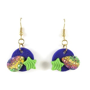 May include: A pair of dangle earrings with a blue circle, a green star, and a colorful patterned teardrop shape. The earrings have gold hooks.