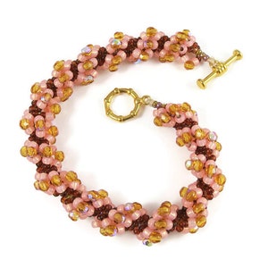 May include: A pink and brown beaded bracelet with a gold clasp. The bracelet is made of small, round beads that are arranged in a spiral pattern.