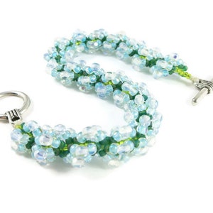 May include: A beaded bracelet with light blue and green beads. The bracelet has a silver toggle clasp.