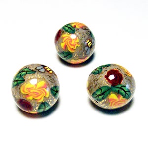 May include: Three round glass beads with a gold background and floral designs. The beads are decorated with yellow, red, and green flowers and leaves.