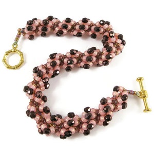 May include: A pink and brown beaded bracelet with a gold clasp and toggle closure.