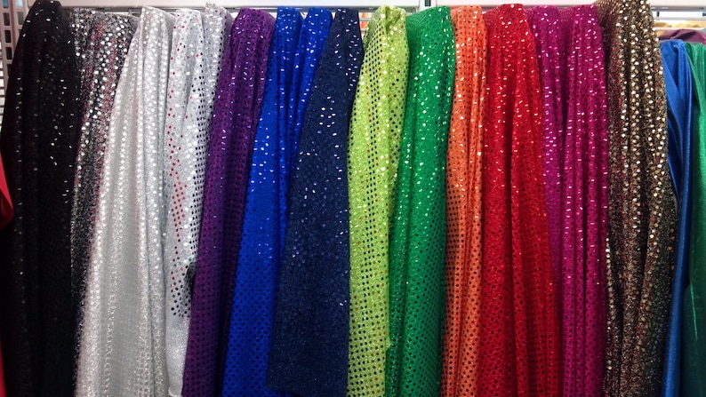 Puede incluir: Una variedad de telas con lentejuelas en diferentes colores, incluyendo negro, plateado, morado, azul, verde, naranja, rojo, rosa, marr&oacute;n y dorado.