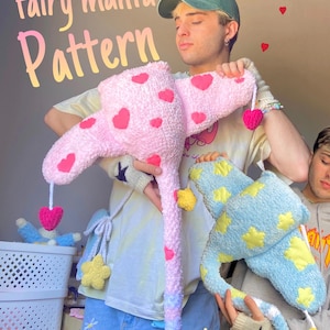 Puede incluir: Patrón de manta de hadas de felpa hecho a mano. Uno es rosa con corazones rojos, el otro azul con estrellas amarillas. El texto "fairy manta Pattern" se muestra en degradado. Cada manta tiene un corazón o una estrella colgante.