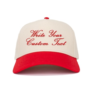 May include: A beige and red trucker hat with the text "Write Your Custom Text" embroidered in red.