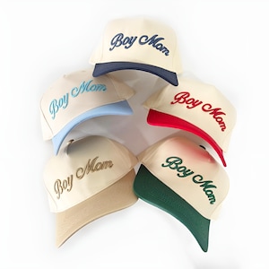 May include: Five baseball caps with the text "Boy Mom" embroidered on the front. The caps are in different colours, including beige, blue, red, and green.