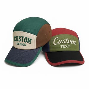 May include: Two custom design caps. One cap is green, brown, and navy blue with "CUSTOM DESIGN" embroidered on the front. The other cap is red, green, black, and navy blue with "Custom TEXT" embroidered on the front.
