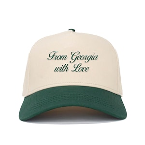 May include: A beige and green baseball cap with the text "From Georgia with Love" embroidered in green on the front.