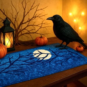 Könnte beinhalten: Eine Halloween-Dekoration mit einer schwarzen Krähenfigur, Kürbissen und Laternen. Ein blauer Tischläufer mit Mond- und Astmuster liegt auf einem Holztisch. Die Szene wird von warmem Licht beleuchtet und erzeugt eine gruselige Atmosphäre.