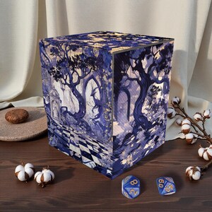 May include: A cube-shaped storage box with a fantasy forest scene in shades of blue and white. The box features a checkered floor design and is surrounded by dice and cotton sprigs. The box is likely for storing tabletop gaming accessories.