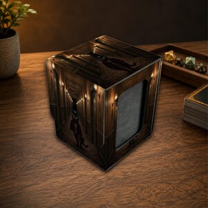 May include: A square-shaped deck box for trading cards featuring a dark, atmospheric hallway illustration with a cat figure in a suit. The box has a deep brown color palette, warm wall lighting, and a gray interior compartment for card storage.