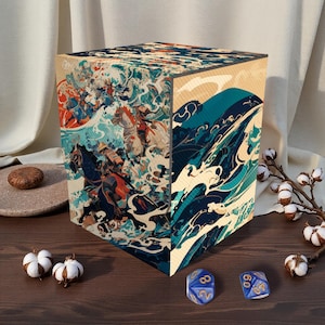 May include: A wooden box with a Japanese-inspired design featuring warriors on horseback and ocean waves in shades of blue, red, and beige. The box is cube-shaped and has a natural wood grain. Two blue dice with white numbers are in front of the box.