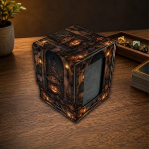 May include: A square deck box featuring a dark, atmospheric illustration of a scarecrow holding a glowing jack-o'-lantern. The design includes stone archways, lanterns, and autumn foliage in shades of brown, orange, and black. The box has a rectangular cutout on the front panel.