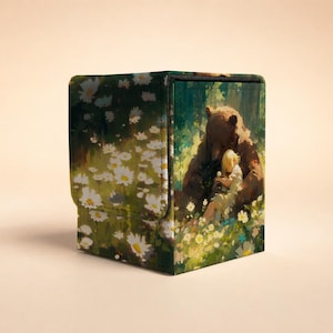 May include: A square deck box featuring a printed illustration of a brown bear sitting in a field of white daisies with a small child. The box has a textured surface and a hinged lid, displaying a vibrant green and white floral forest scene.