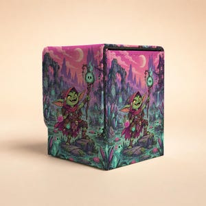 May include: A square deck box featuring a vibrant illustration of a green goblin holding a glowing staff and a pink potion bottle. The scene depicts a swampy landscape with purple mountains, crescent moons, and glowing blue magical elements.
