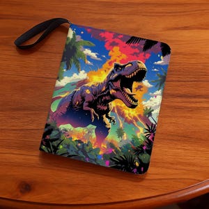 May include: A colorful clutch featuring a Tyrannosaurus Rex illustration. The design includes a vibrant sky, palm trees, and a fiery background. The clutch has a black wrist strap and is likely made of a durable material.