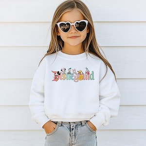 May include: White sweatshirt with a colorful Disney Land graphic featuring Mickey Mouse, Donald Duck, Minnie Mouse, Goofy, Pluto, and Daisy Duck.