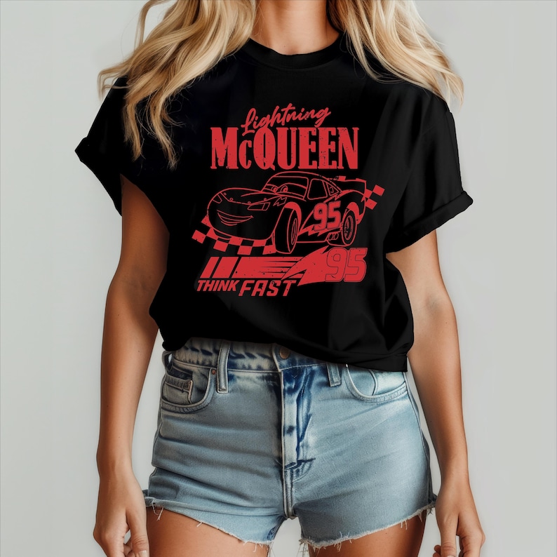 Może przedstawiać: Czarny T-shirt z czerwoną grafiką Błyskawicy McQueena z filmu Auta. Grafika zawiera tekst "Lightning McQueen", "Think Fast" i numer "95".