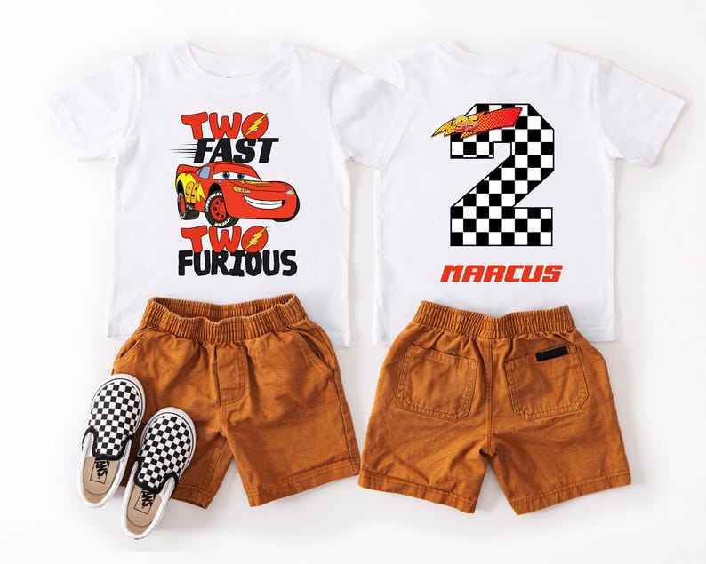Peut inclure: Deux t-shirts blancs avec des motifs de voiture de course et le texte "Two Fast Two Furious" et un num&eacute;ro 2 &agrave; damier avec le nom "Marcus". Ils sont assortis &agrave; des shorts marron et des chaussures &agrave; enfiler &agrave; carreaux.