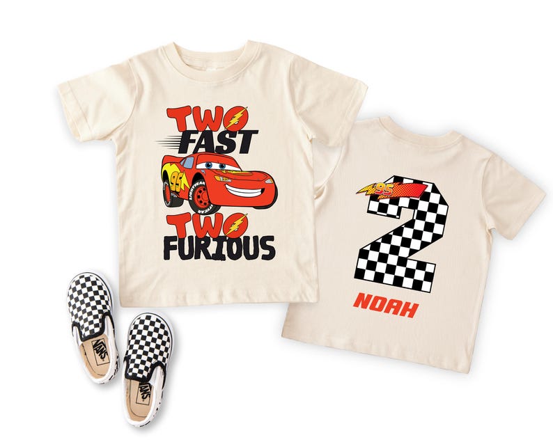 Peut inclure: Deux t-shirts cr&egrave;me sur le th&egrave;me de Cars. L'un pr&eacute;sente Flash McQueen et le texte "TWO FAST TWO FURIOUS". L'autre affiche un num&eacute;ro 2 &agrave; damier et le nom "NOAH". Des chaussures &agrave; enfiler &agrave; carreaux noirs et blancs sont &eacute;galement visibles.