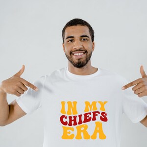 May include: A white t-shirt with the text "IN MY CHIEFS ERA" in red and yellow retro font.