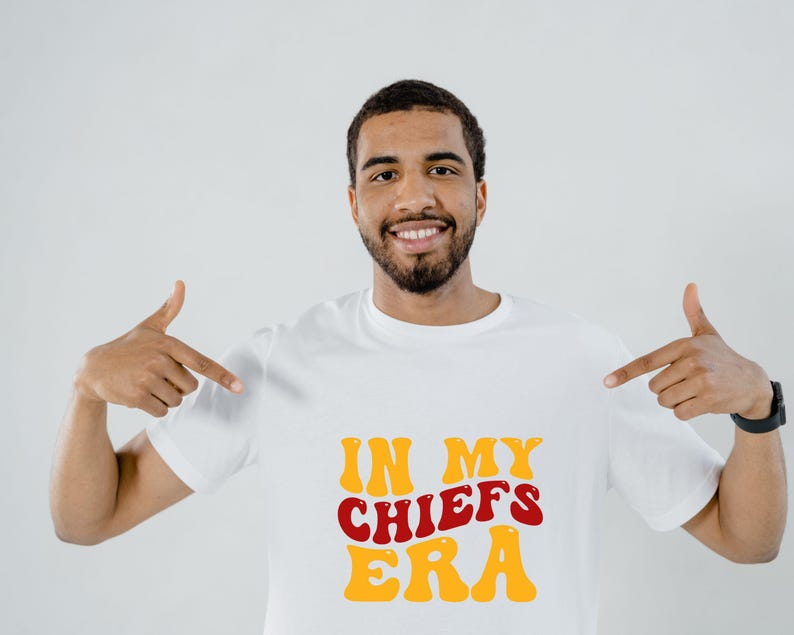 May include: A white t-shirt with the text "IN MY CHIEFS ERA" in red and yellow retro font.
