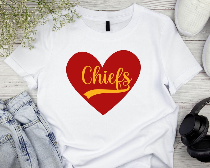 May include: White t-shirt with a red heart and the word "Chiefs" in yellow lettering.