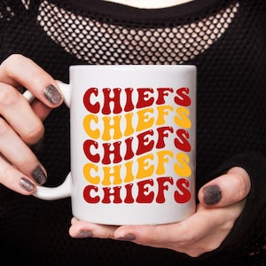 May include: White ceramic mug with the word "CHIEFS" repeated five times in a retro font. The text is in red and yellow.