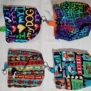 May include: Four fabric treat pouches with drawstring closures and metal clips. Top left features black fabric with colorful text and hearts. Top right has a rainbow gradient with dog-themed words. Bottom left shows red, blue, and yellow patterns. Bottom right displays various dog breeds.