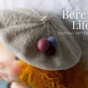 May include: A close-up of a doll wearing a light grey knitted beret with three colourful felt balls on top. The beret has a simple stitch pattern and the doll has long, curly orange hair. The text "Beret Life" and "Knitting Pattern" is visible in the background.