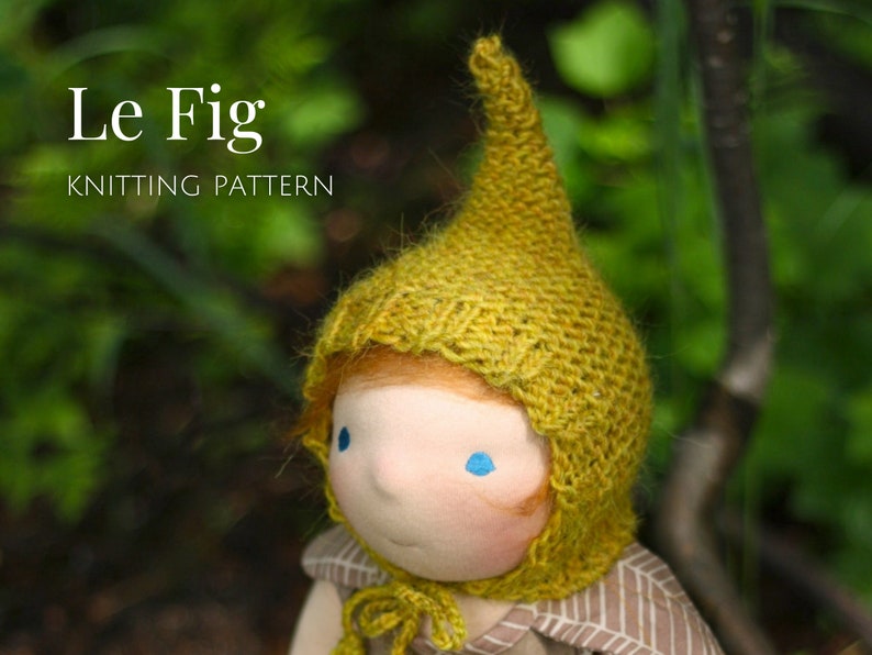 K&ouml;nnte beinhalten: Eine Puppe tr&auml;gt eine gelbe Strickm&uuml;tze mit einer spitzen Spitze. Die M&uuml;tze hat eine Strickstruktur und hei&szlig;t "Le Fig" Strickmuster.