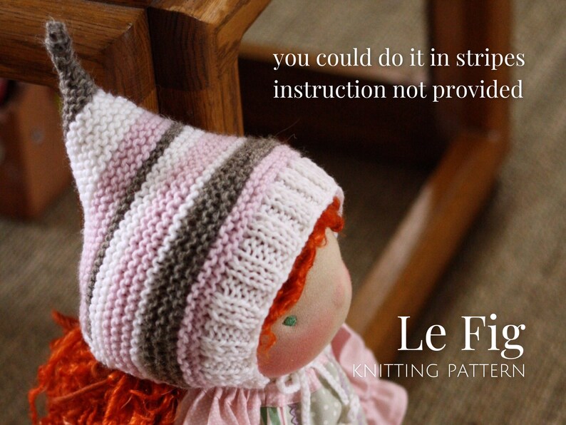 K&ouml;nnte beinhalten: Eine gestrickte Puppenm&uuml;tze mit rosa, wei&szlig;en und braunen Streifen. Die M&uuml;tze hat eine spitze Spitze und wird von einer Puppe mit roten Haaren getragen. Der Text "Le Fig Knitting Pattern" ist im Bild sichtbar.
