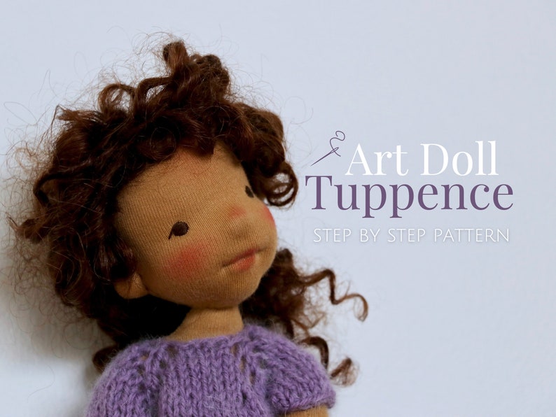 May include: A brown-skinned art doll with curly brown hair wearing a purple knitted sweater. The doll is looking up and has a sweet expression. The text "Art Doll Tuppence Step by Step Pattern" is in the background.
