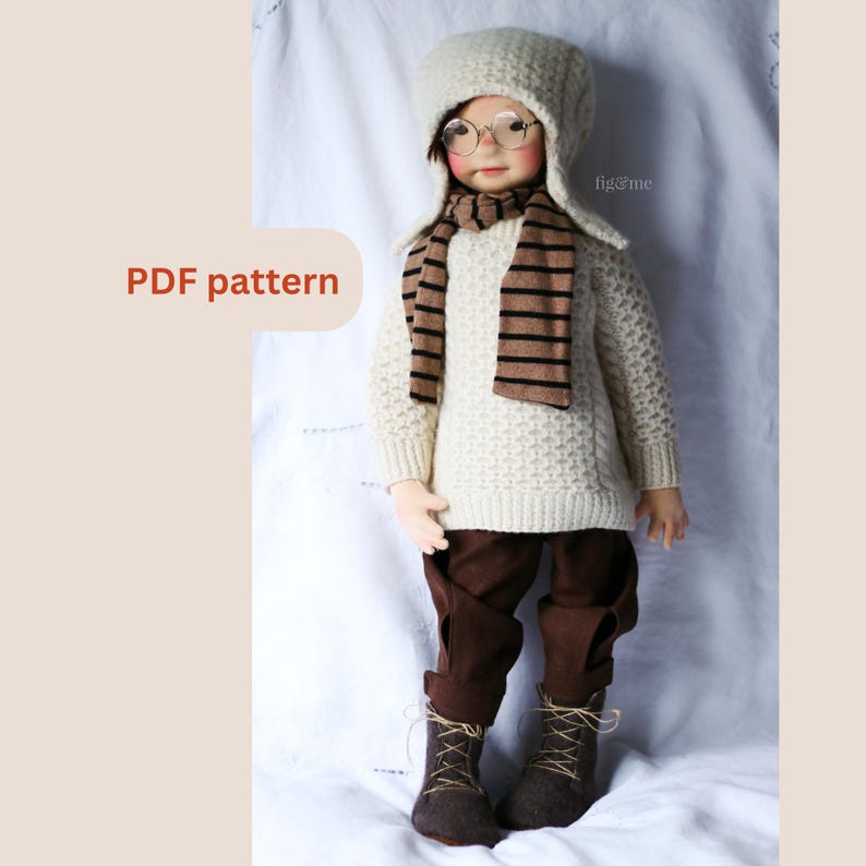 K&ouml;nnte beinhalten: Ein wei&szlig;er Strickpullover mit einem braun-wei&szlig; gestreiften Schal und einer wei&szlig;en Strickm&uuml;tze mit braunem Rand. Die Puppe tr&auml;gt eine braune Hose und braune Stiefel. Der Text "fig&me" ist auf der M&uuml;tze zu sehen.