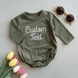 May include: A green long-sleeved baby onesie with white embroidered text that says "Custom Text".