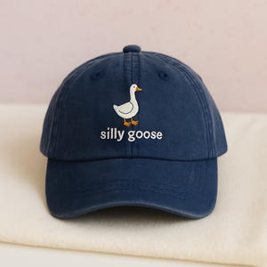 May include: A navy blue baseball cap with an embroidered white goose and the text "silly goose".