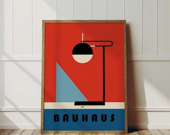 May include: A framed poster with a red background and a black and white geometric lamp design. The poster has the word "BAUHHAUS" in blue letters at the bottom.