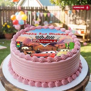 May include: A round, pink frosted cake decorated with a Cars-themed image. The image features the text "Happy 2nd Birthday Thomas" and illustrations of characters from the movie. The cake is adorned with pink frosting swirls around the edges.