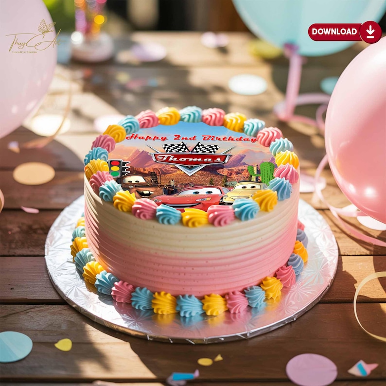 May include: A round birthday cake with a Cars theme. The cake has a pink and white ombre frosting, decorated with colorful frosting swirls. The top features an edible image with the text "Happy 2nd Birthday Thomas" and Cars characters.