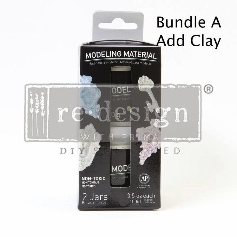May include: Black box of modeling material with the text "MODELING MATERIAL" and "Bundle A Add Clay". The box contains two jars of modeling material, each 3.5 oz (100g). The box also has the text "NON-TOXIC" and "2 Jars".