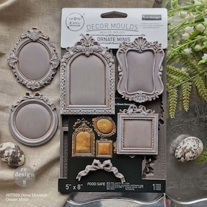 May include: A package of gray ornate mini decor molds with various frame designs. The package includes oval, rectangular, and arched frames, along with a bow. The molds are 5" x 8" and food safe.