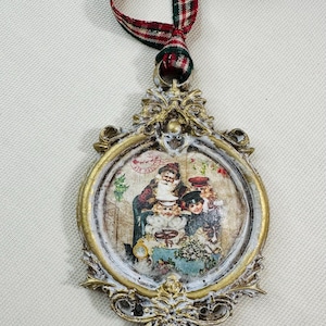 May include: Ornate Christmas ornament with a vintage-style image of Santa Claus and children. The oval-shaped ornament has a gold and white distressed finish, with a red, green, and white plaid ribbon for hanging.
