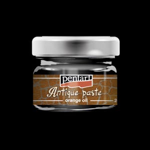 May include: A small glass jar of Pentart Antique Paste with a silver lid. The label features the words "Antique paste" and "orange oil" in a decorative font. The jar is filled with a dark brown substance.