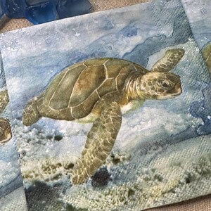 Puede incluir: Servilletas cuadradas con un diseño de acuarela de una tortuga marina nadando en el océano. La tortuga tiene un caparazón marrón y verde y está rodeada de agua azul y blanca. Las servilletas son de material suave.
