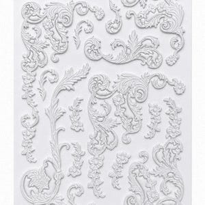 May include: A collection of white, ornate decorative embellishments featuring floral and scroll designs. The various pieces include borders, sprigs, and individual floral elements, perfect for craft projects or home decor.