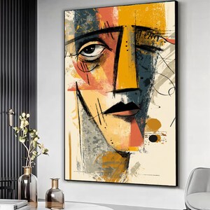 Puede incluir: Impresión artística abstracta de un retrato que presenta un rostro estilizado con líneas audaces y colores vibrantes. La obra de arte utiliza una paleta de amarillo, naranja, azul y gris, creando una estética moderna y expresiva. El rostro está enmarcado en un borde negro.