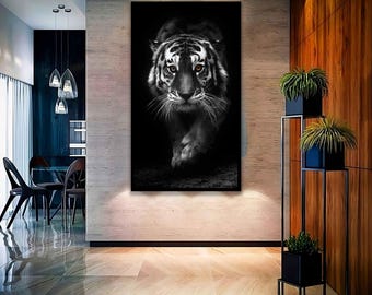 May include: A black and white photograph of a tiger walking towards the camera. The tiger has bright yellow eyes and is in focus. The background is blurred.